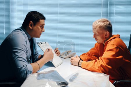 Foto de Abogado hablando con criminal antes del juicio y señalando la lista de testigos - Imagen libre de derechos