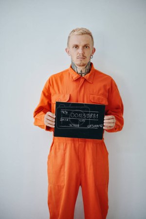 Photo for Mugshot of suspect in ornage uniform holding sign board - Royalty Free Image