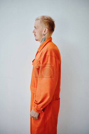 Photo for Profile portrait of arrested young man in orange jail uniform - Royalty Free Image