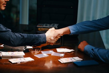 Photo for Cropped image of drug dealer and buyer shaking hands over table with money and small bags with tablets - Royalty Free Image