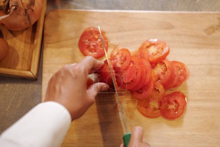 Téléchargez les photos : Image rapprochée de cuisinier coupant des tomates fraîches en fines tranches, vue d'en haut - en image libre de droit