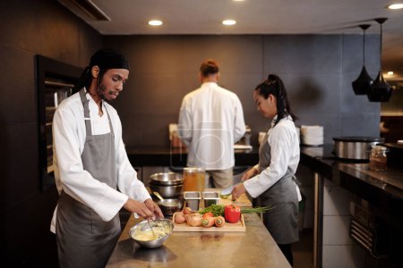 Foto de Equipo de grandes profesionales trabajando en cocina moderna de restaurante de lujo - Imagen libre de derechos