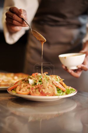 Téléchargez les photos : Restaurant cuisinier verser vinaigrette sur salade fraîche délicieuse - en image libre de droit