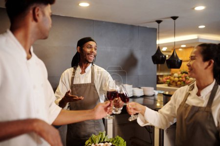 Photo for Team of joyful cooks drinking wine when celebrating restaurant opening - Royalty Free Image