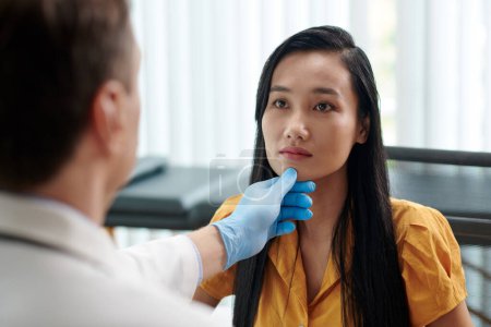 Téléchargez les photos : Chirurgien plasticien examinant le visage de la femme avant de recommander son traitement - en image libre de droit