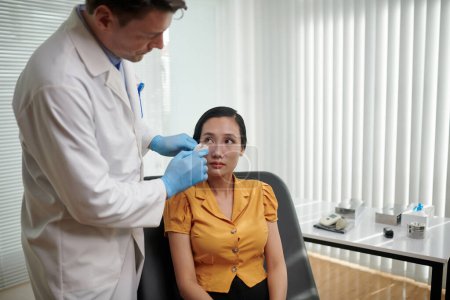 Photo for Plastic surgeon removing nose patch from face of female patient - Royalty Free Image
