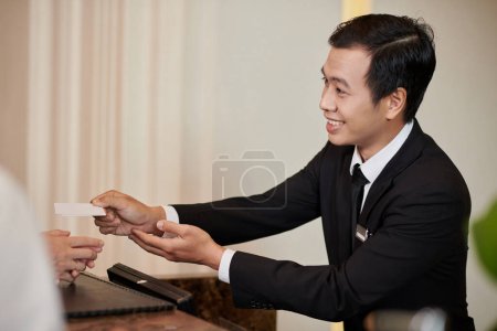 Photo for Smiling hotel recceptionist giving electronic keys to guests - Royalty Free Image