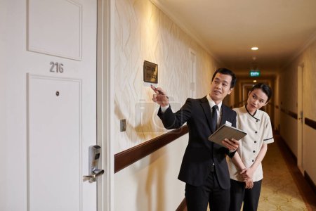 Téléchargez les photos : Gestionnaire de l'hôtel expliquant bonne quelles chambres doivent être nettoyées - en image libre de droit