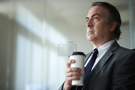 Photo for Portrait of serious mature businessman drinking cup of morning coffee - Royalty Free Image