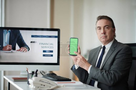 Foto de Empresario maduro mostrando aplicación moblie que puede ayudar a gestionar las finanzas - Imagen libre de derechos