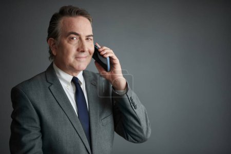 Photo for Portrait of happy businessman talking on phone and looking at camera - Royalty Free Image