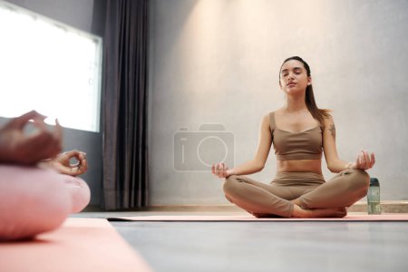 Téléchargez les photos : Jeune femme respirant calmement en méditant en position lotus - en image libre de droit