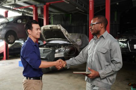 Photo for Happy owner shaking hand of car service worker - Royalty Free Image