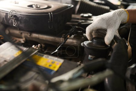 Téléchargez les photos : Image rapprochée du mécanicien changeant l'huile dans la voiture du client - en image libre de droit