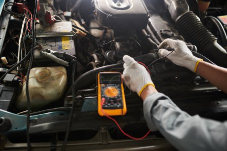 Photo for Car service worker using multimeter when checking car engine - Royalty Free Image