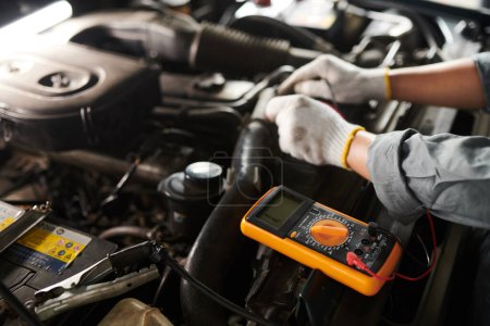 Photo for Closeup image of mechanic using multimeter when checking car engine - Royalty Free Image