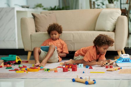 Foto de Hermanos pasando tiempo en casa jugando con varios juguetes - Imagen libre de derechos