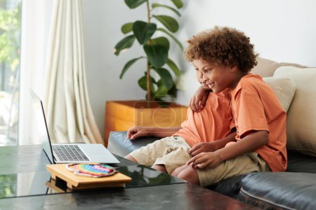 Téléchargez les photos : Enfants excités regardant la vidéo de leur blogueur préféré sur ordinateur portable à la maison - en image libre de droit