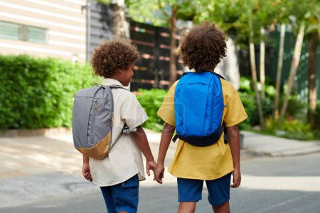 Foto de Niño cogido de la mano de su hermano menor cuando están caminando a la escuela por la mañana - Imagen libre de derechos