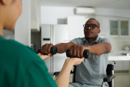 Téléchargez les photos : Physiothérapeute contrôlant les haltères de levage de patients pour entraîner les muscles - en image libre de droit