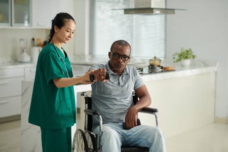 Téléchargez les photos : Physiothérapeute demandant au patient handicapé de sortir le bras suivant avec haltère - en image libre de droit