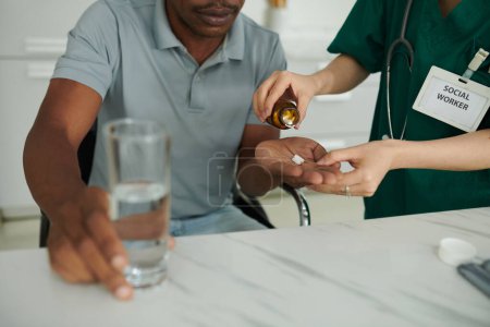 Photo for Closeup image of social worker giving supplements to sick patient when visiting him at home - Royalty Free Image