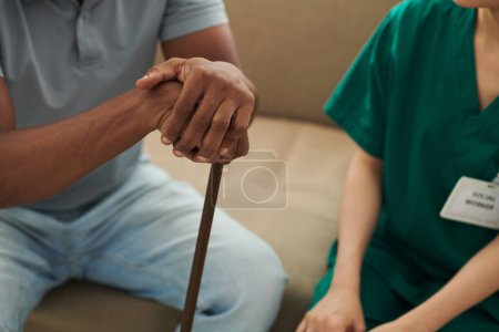 Patient stützt sich im Gespräch mit Sozialarbeiterin auf Gehstock