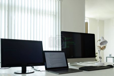 Téléchargez les photos : Ordinateur portable et ordinateurs avec code de programmation sur la table dans le bureau - en image libre de droit