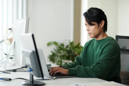 Foto de Retrato de un hombre asiático serio codificando en el portátil en su escritorio de la oficina - Imagen libre de derechos