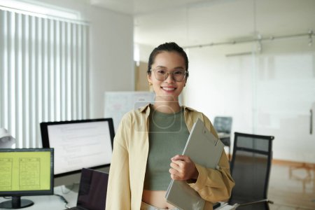 Photo for Portrait of positive IT company employee with clipboard standing in office - Royalty Free Image