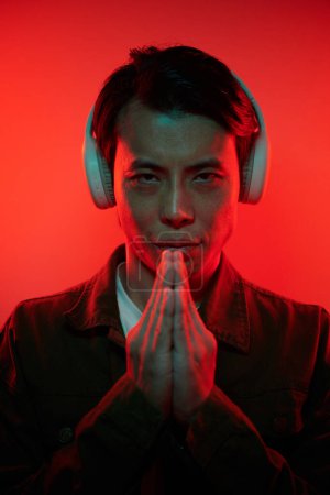 Photo for Hacker in headphones keeping hands in namaste gesture and looking at camera - Royalty Free Image