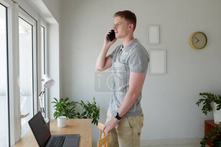Téléchargez les photos : Enrepreneur parler au téléphone avec un collègue lorsque vous travaillez à domicile - en image libre de droit