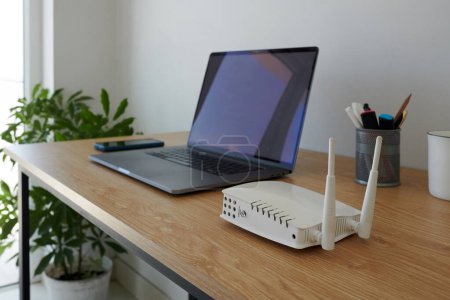 Téléchargez les photos : Routeur Wifi à côté de l'ordinateur portable ouvert de l'homme d'affaires travaillant de la maison - en image libre de droit