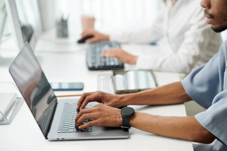 Téléchargez les photos : Mains de développeur de logiciels avec smartwatch travaillant sur ordinateur portable dans le bureau - en image libre de droit