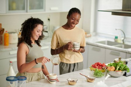Foto de Compañeros de cuarto alegre beber café y hacer el desayuno en la cocina - Imagen libre de derechos