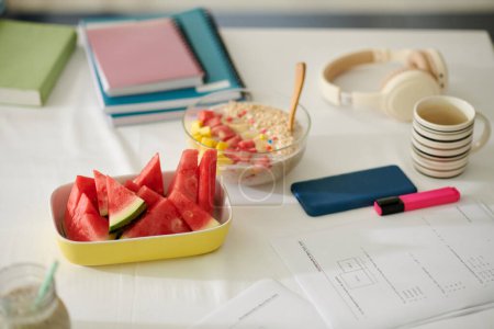 Photo for Bowl of cut watermelon next to papers for math exam - Royalty Free Image