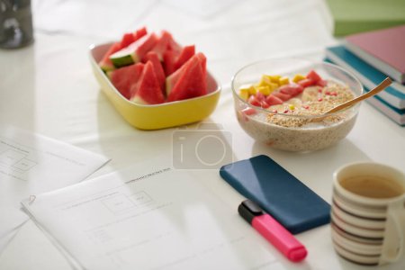 Photo for Math test papers next to bowl of oatmeal and cut watermelon - Royalty Free Image