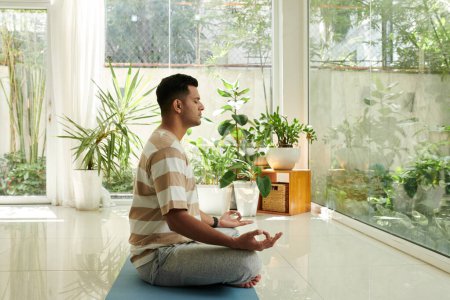 Foto de Hombre tranquilo disfrutando de la práctica de meditación matutina en casa - Imagen libre de derechos