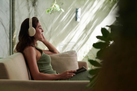 Téléchargez les photos : Jeune femme fermant les yeux en écoutant de la musique dans les écouteurs - en image libre de droit