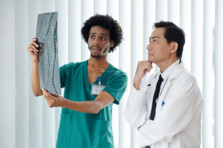 Téléchargez les photos : Infirmière montrant radiographie de la colonne vertébrale du patient au médecin - en image libre de droit