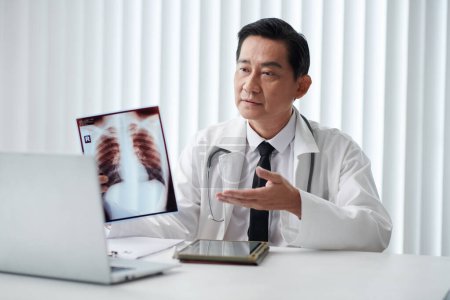 Téléchargez les photos : Médecin montrant la radiographie pulmonaire lorsque vous parlez au patient lors d'une réunion en ligne - en image libre de droit
