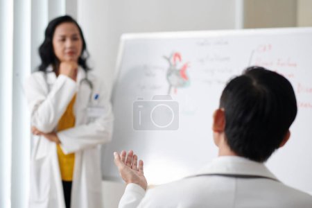 Photo for Doctor asking question in seminar with prominent cardiologist - Royalty Free Image