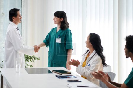 Téléchargez les photos : Docteur serrant la main de l'infirmière saluant un nouveau membre de l'équipe - en image libre de droit