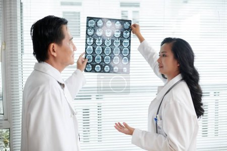 Téléchargez les photos : Les médecins discutent de l'image radiographique des disques de colonne vertébrale du patient malade - en image libre de droit