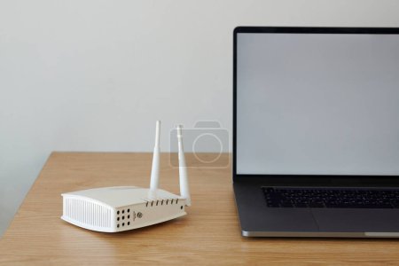 Foto de Router Wifi junto al portátil abierto en escritorio de madera - Imagen libre de derechos