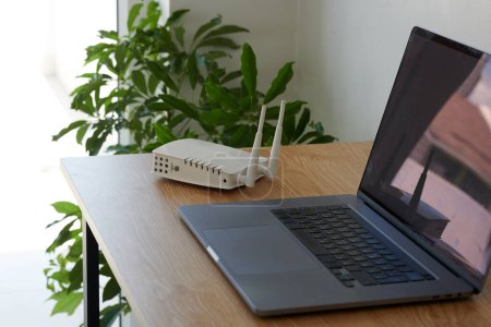 Téléchargez les photos : Routeur Wifi et ordinateur portable sur bureau sur pigiste travaillant depuis la maison - en image libre de droit