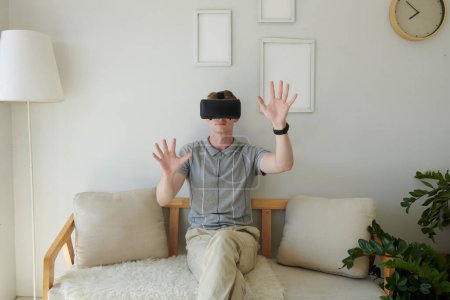 Téléchargez les photos : Jeune homme en réalité virtuelle casque toucher des objets invisibles - en image libre de droit