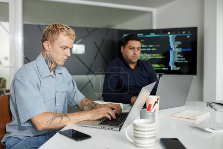 Foto de Programador de software serio codificación en el ordenador portátil en el escritorio de la oficina - Imagen libre de derechos