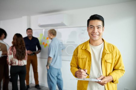 Photo for Portrait of smiling startupper taking notes in document on clipboard - Royalty Free Image