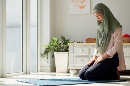Téléchargez les photos : Calme femme d'âge moyen priant à la maison, l'espoir et la foi concept - en image libre de droit